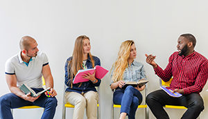 A group of female and male students sitting on chairs, discussing.