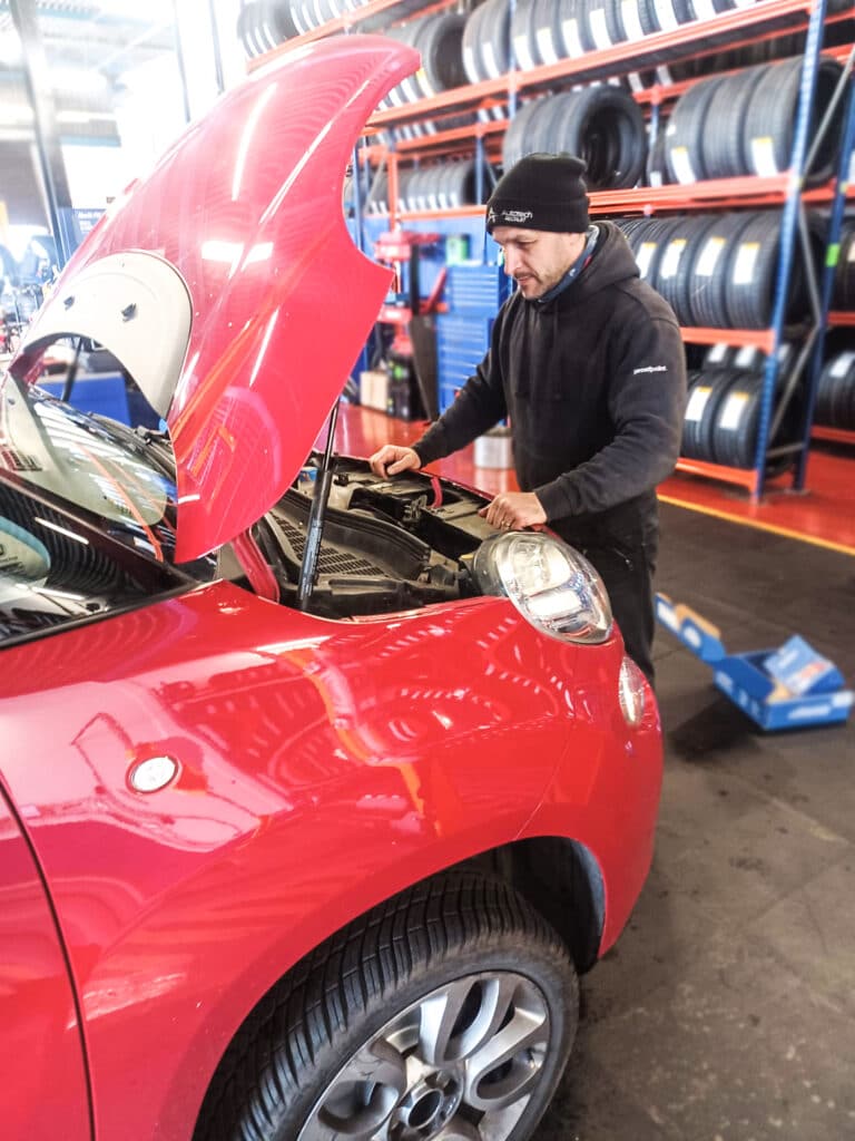 Contract Vehicle Technician Roberto working on the engine of a red car for Autotech Recruit