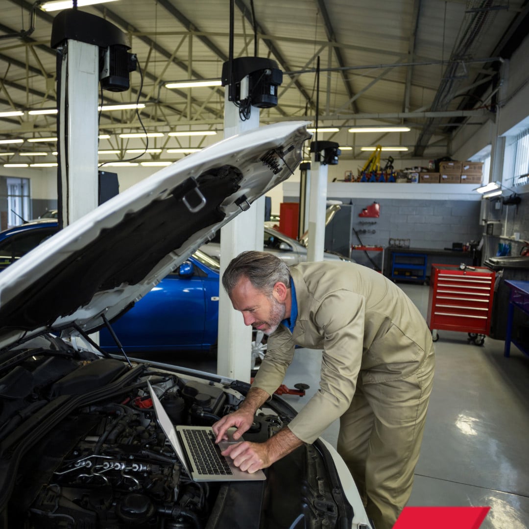 Vehicle Technician Working on Car In Workshop